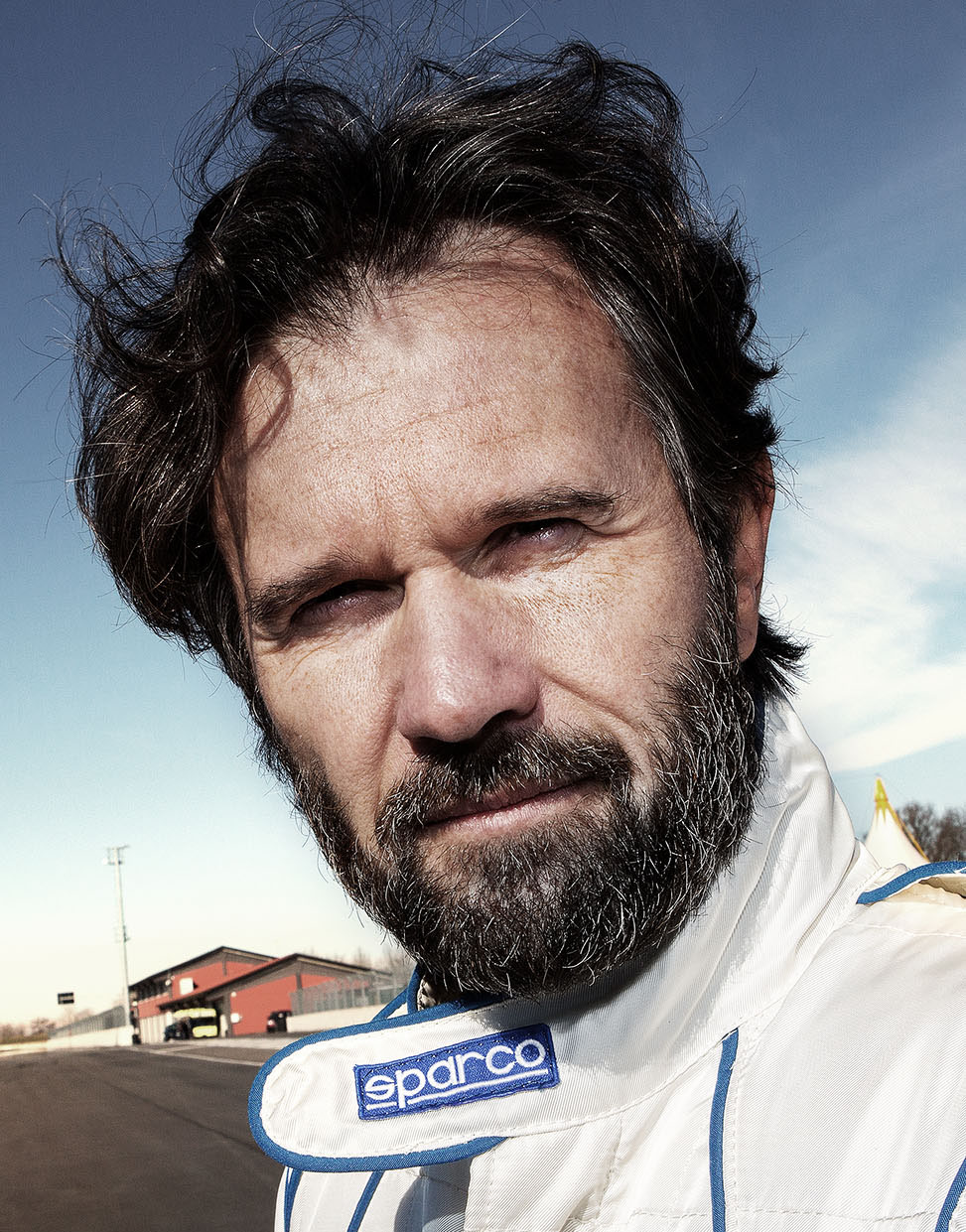 Tony Hassler in racing gear, intense expression on racetrack