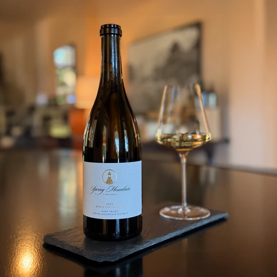 A bottle of 2023 Spring Mountain Vineyard Estate Chardonnay and a glass on a tasting plate.