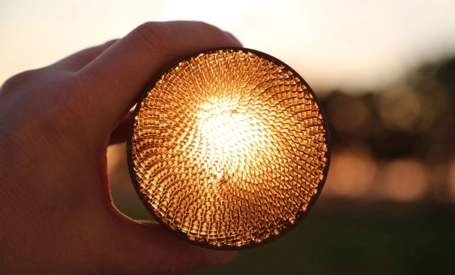 A hand holding the catalyst-coated honeycomb, displaying it in cross-section view, where hydrogen and CO2 react into methane.