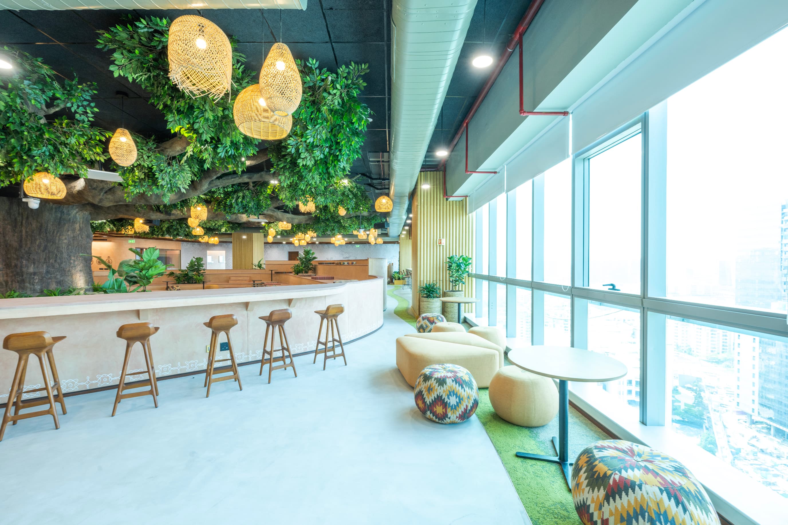 The Tree of Knowledge is a hand-sculpted concrete trunk crowned with silk foliage. Coffee points at the canopy's edge extend the amphitheatre into places to pause, reinforcing the traditional idea of gathering and learning beneath a tree.