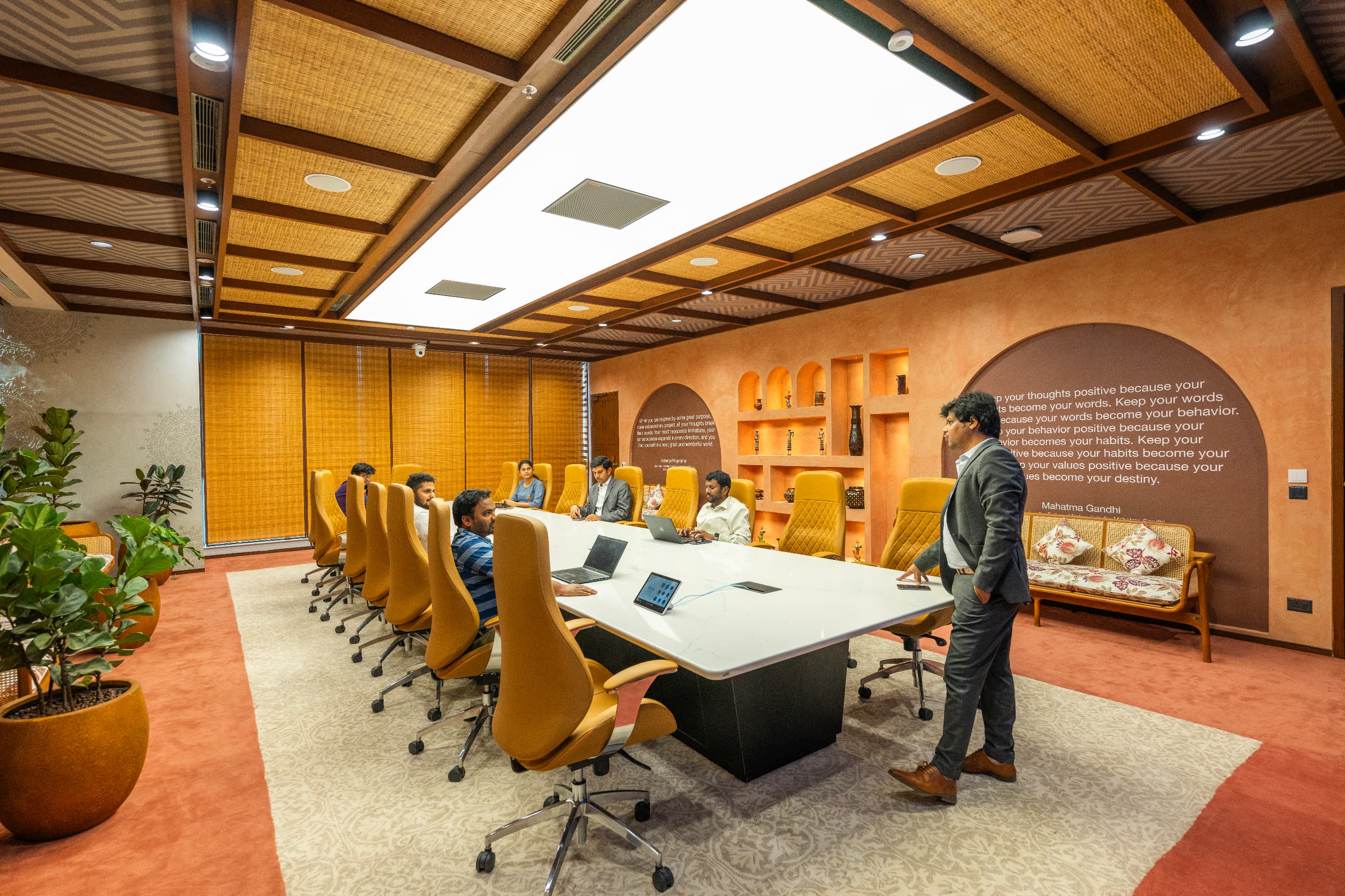 The 20-seat boardroom sets curated artefacts into terracotta niches beneath a coffered bamboo ceiling. Quotes from Indian legends are applied directly to the wall.