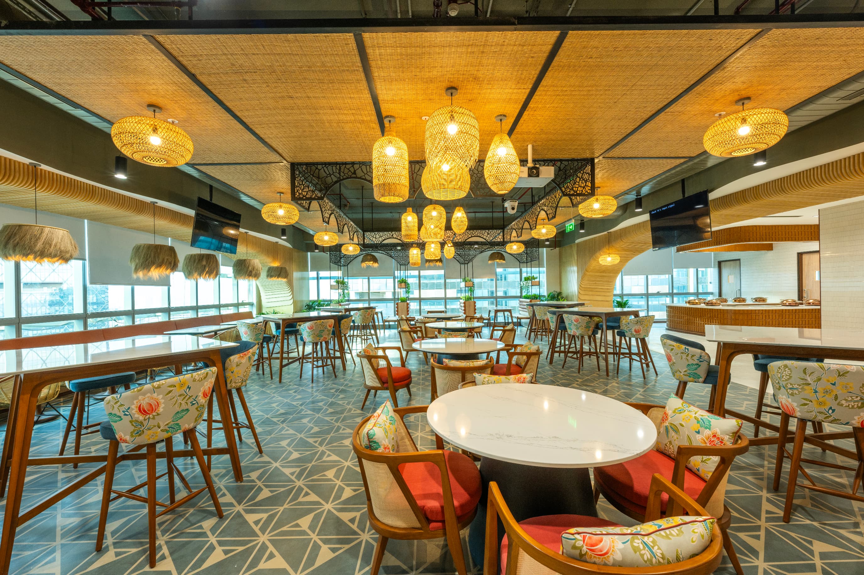 The 92-seat cafeteria sits at the social end of the floor. Woven mat ceilings, rattan pendants and hand-printed upholstery carry the craft palette through to dining.