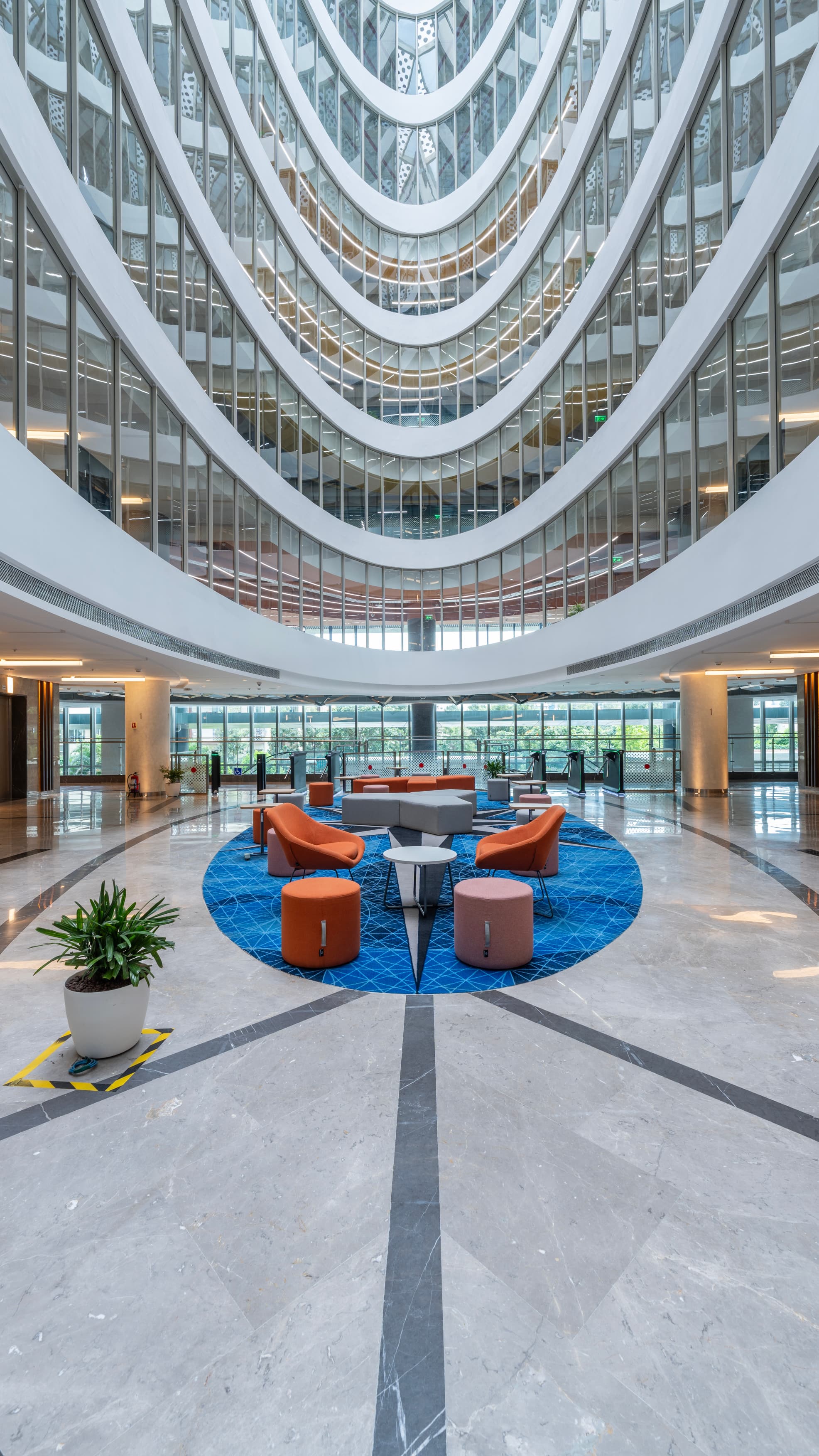 An eight-storey central atrium drops daylight deep into the plan. Its radius is picked up in custom curved gypsum forms and pendant lighting rings, lending every level a subtle sense of spin.