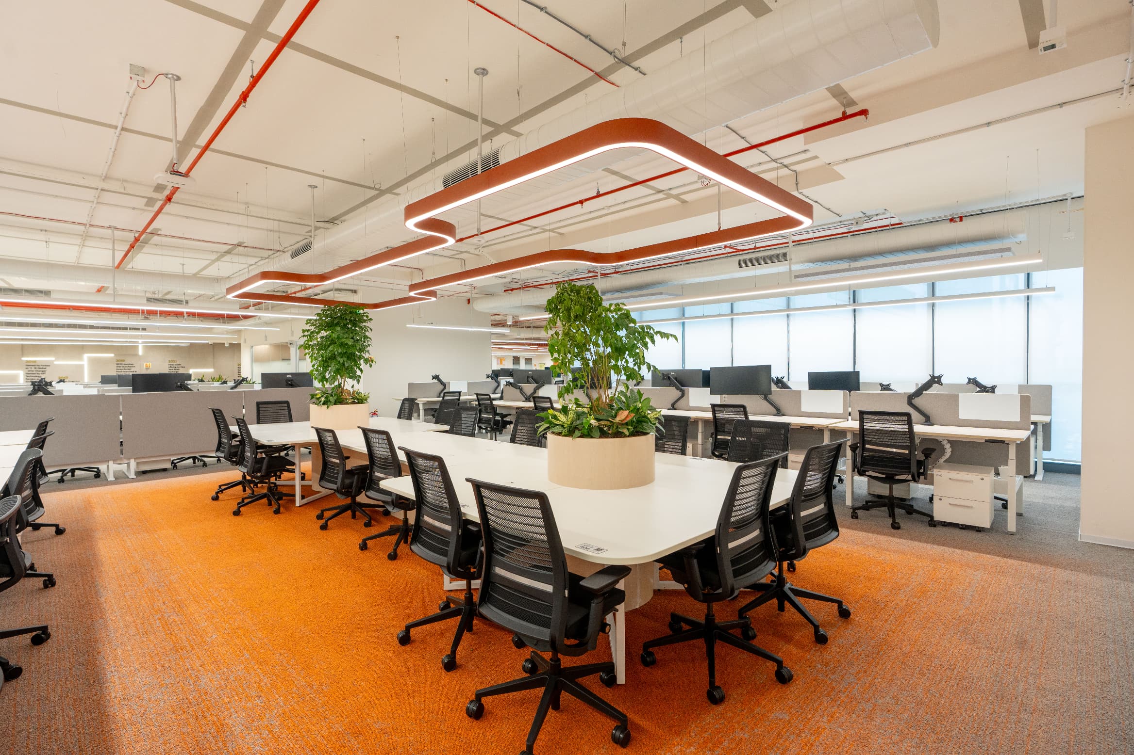 A sculptural ring pendant marks the collaboration table at the centre of the wing. Along the corridor behind it, LED-lit wooden panels form a history wall chronicling the company's journey.