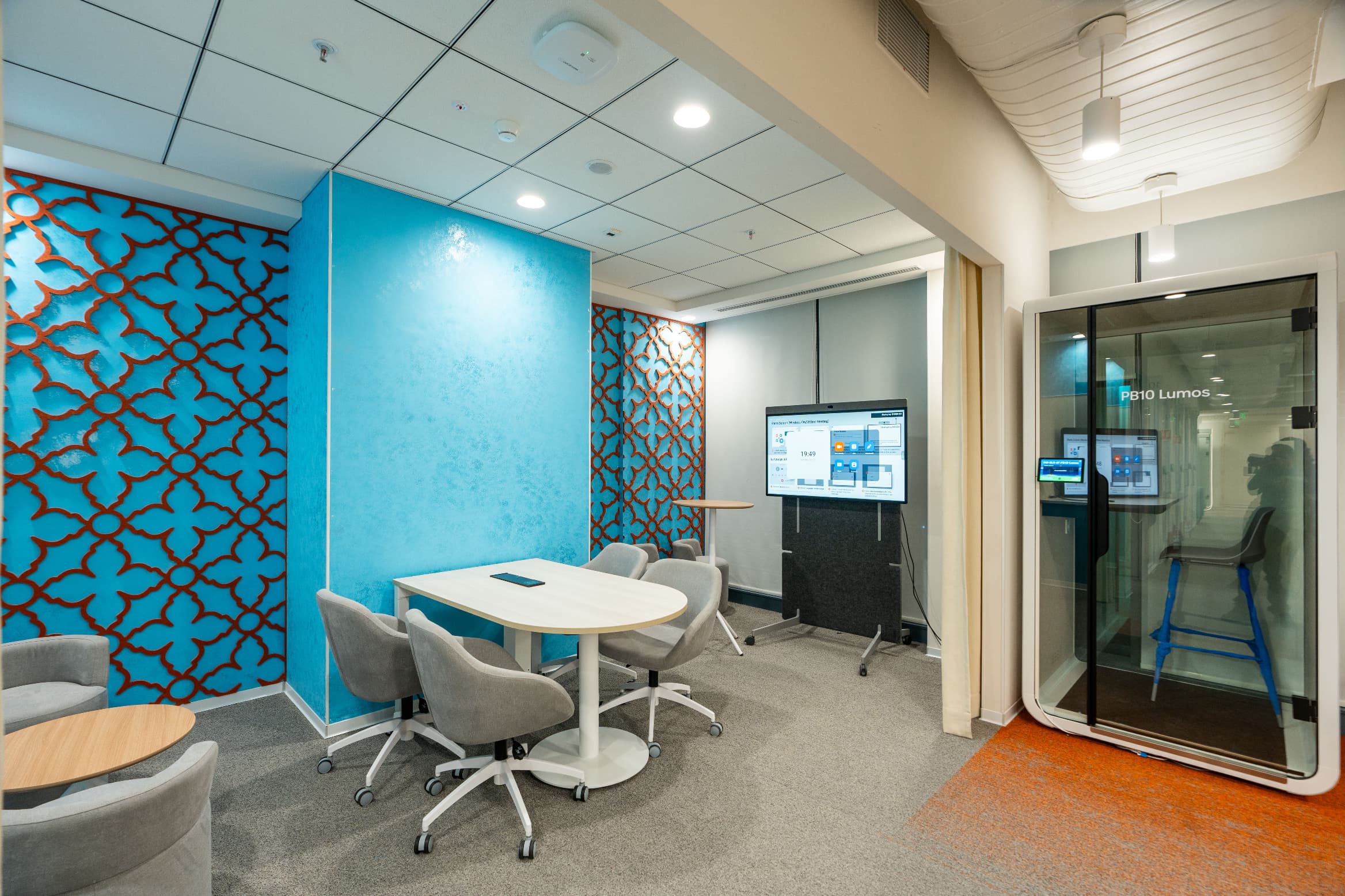 The blue wing carries its own palette and pattern language. Mobile screens and a self-booking phone booth keep meeting capacity flexible without adding enclosed rooms.