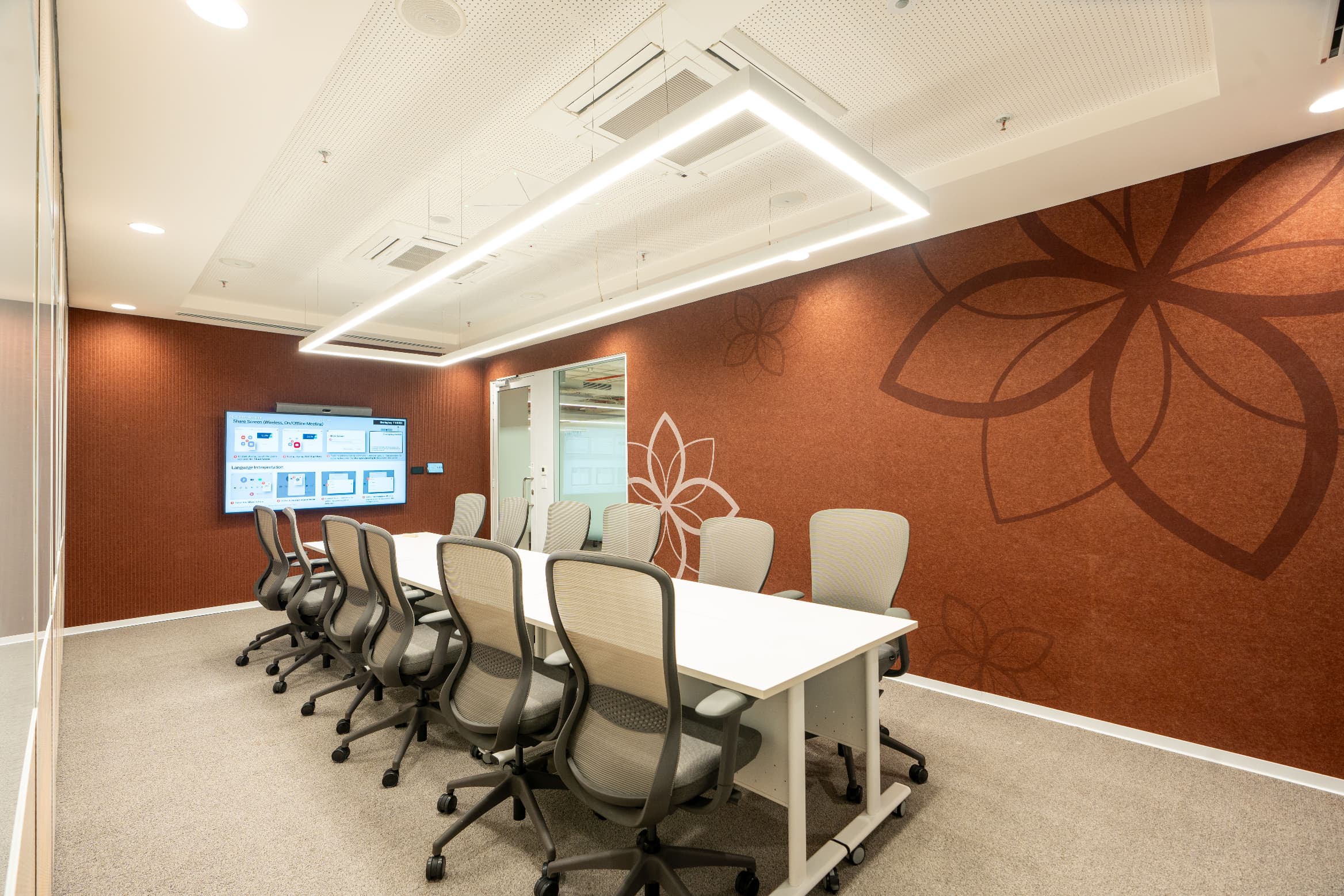 Meeting rooms are lined in acoustic panelling and finished with organic motif graphics. Curved glass partitions with translucent frosting hold privacy while keeping the floor visually continuous.