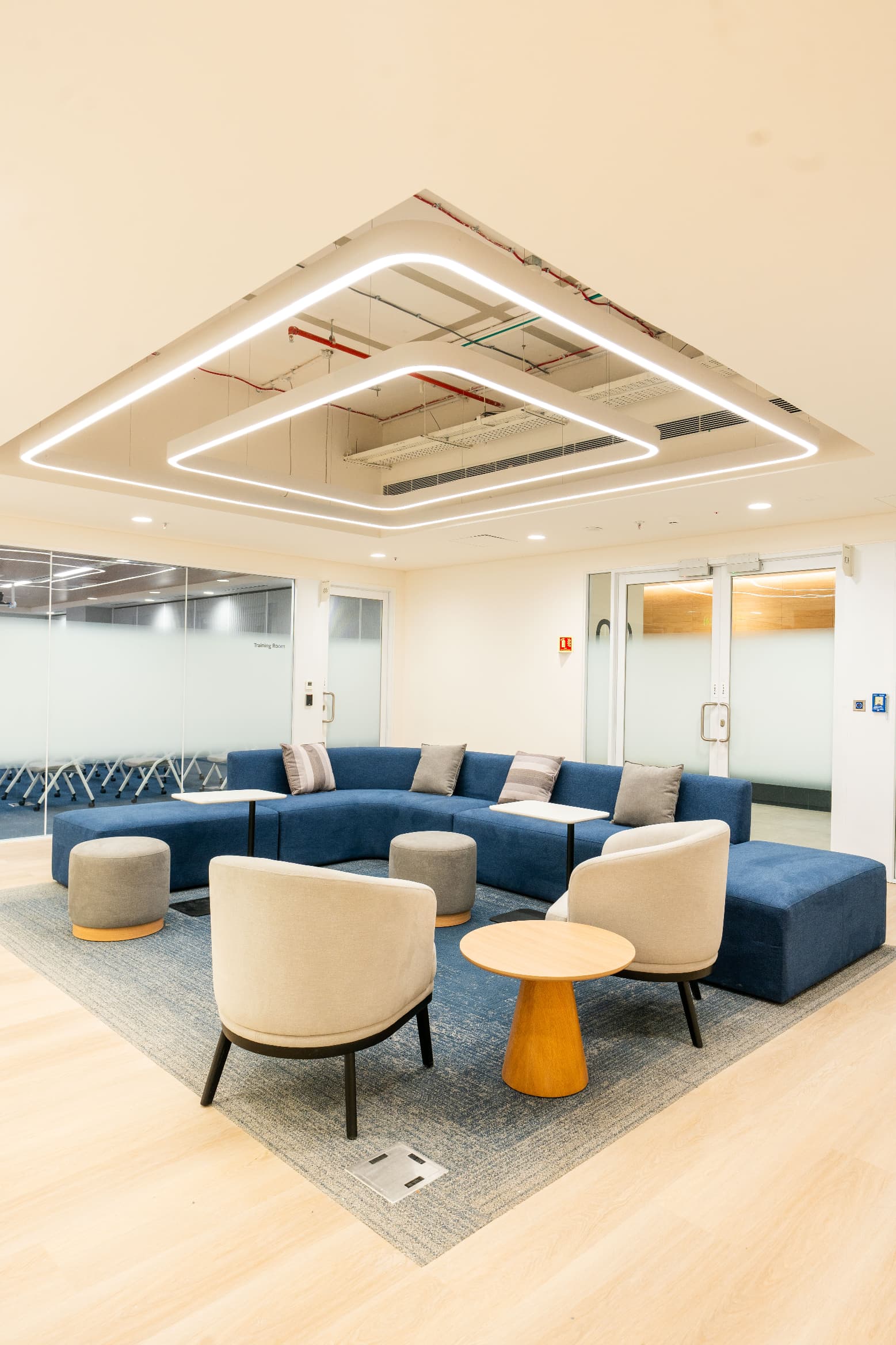 A lounge setting sits immediately outside the 52-seat training room, which opens through sliding-folding doors onto the cafeteria to form a 200-seat all-hands venue.