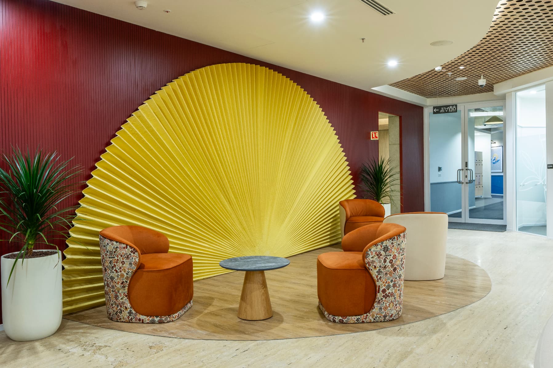 An origami-inspired acoustic felt fan anchors the arrival space against a deep red slatted wall. It is the clearest single expression of the Japanese influence that runs through the wider craft narrative.