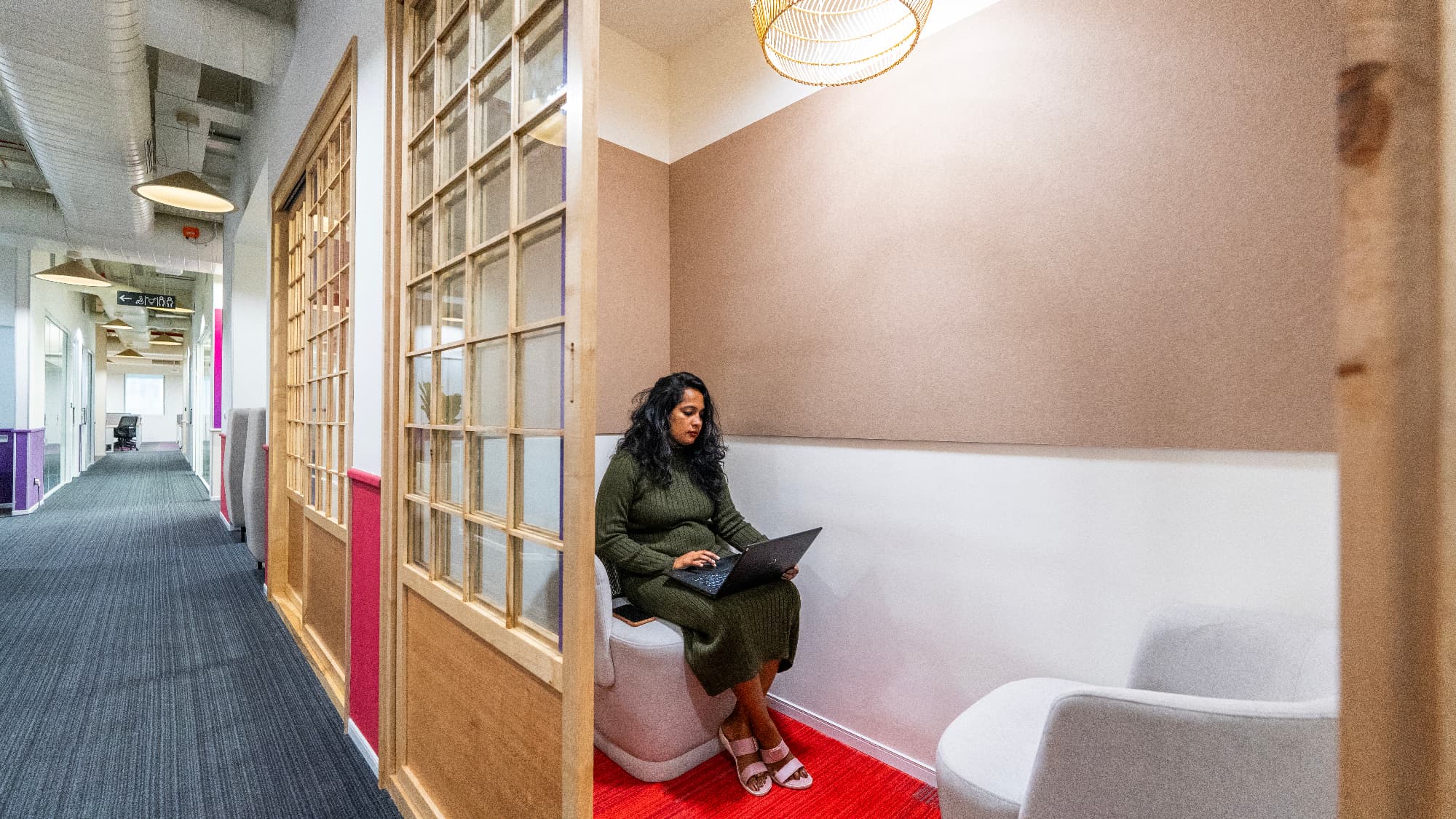 Phone booths are framed with wooden shoji-style sliding doors. The translucent panels give acoustic separation for calls and focused work while keeping the corridor visually light.