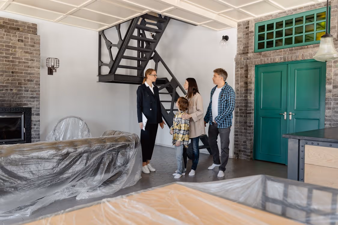 A group of people standing in a room with a staircase and a green doorAI-generated content may be incorrect.