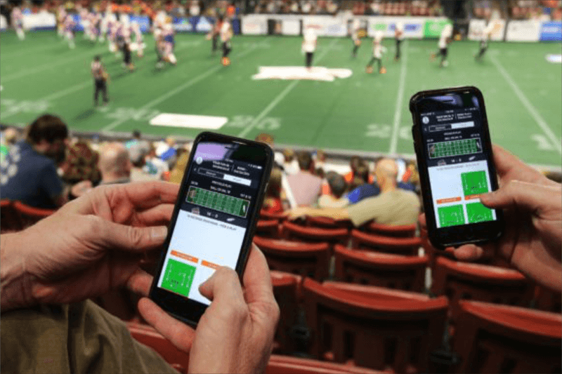 People watching the game on screen on phone while sitting in stadium 