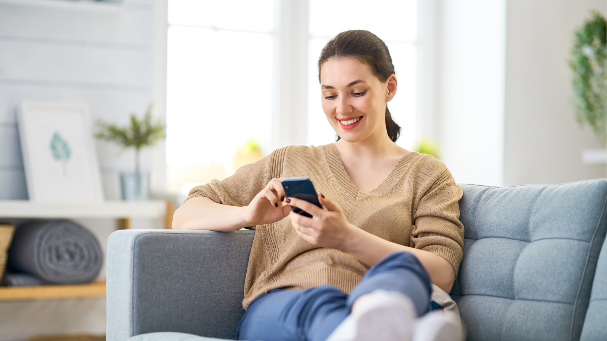 Woman sitting on couch with mobile phone in hand
