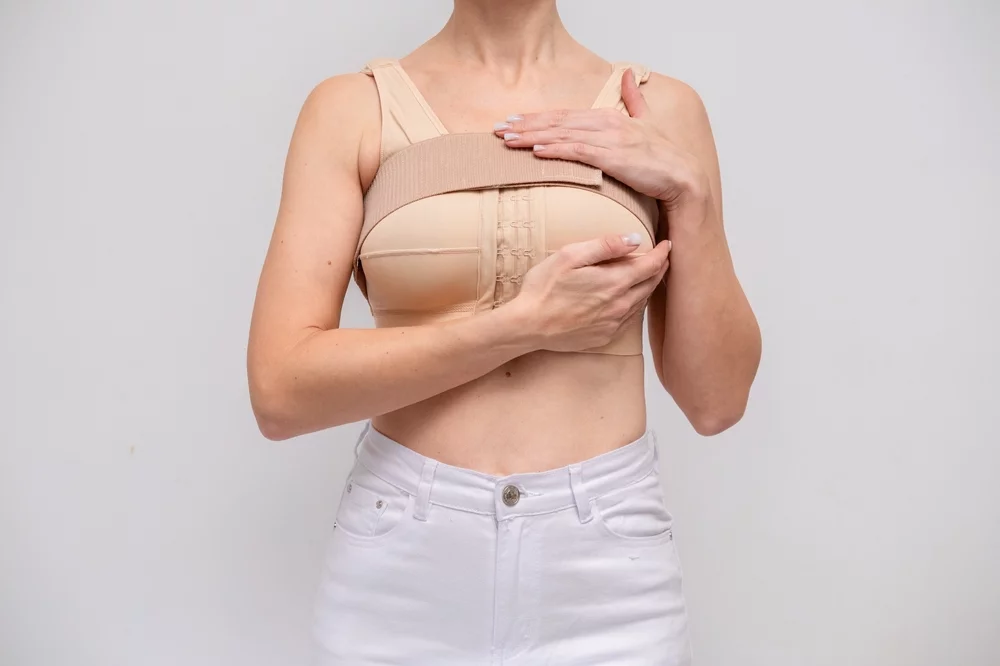 Woman wearing a post-surgical compression bra during breast recovery.