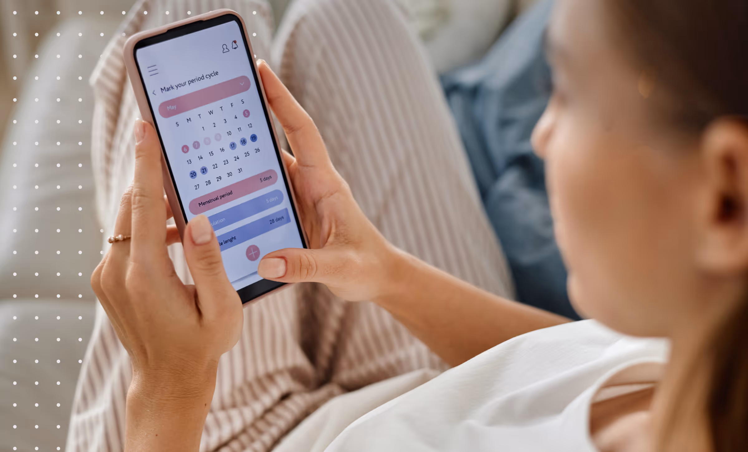 Person holding a smartphone displaying a menstrual cycle tracking app with a May calendar and period details.