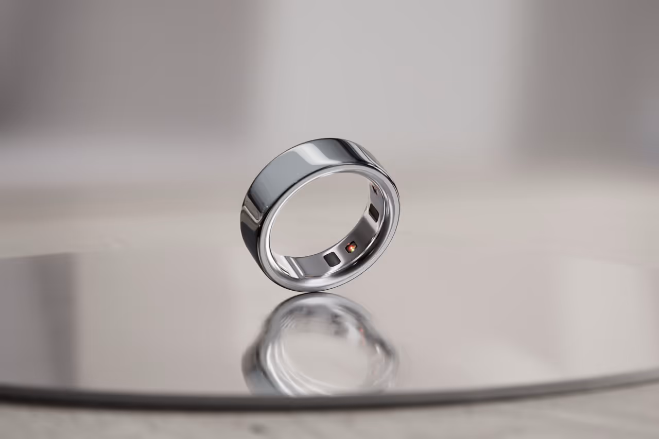 Close-up of a reflective silver ring with sensors on the inner side, placed on a smooth reflective surface.