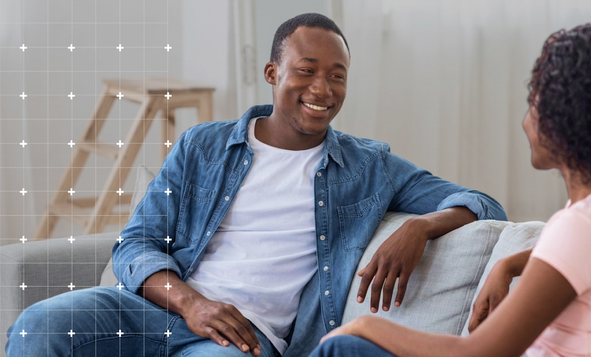 Image of a man and his partner on a sofa talking