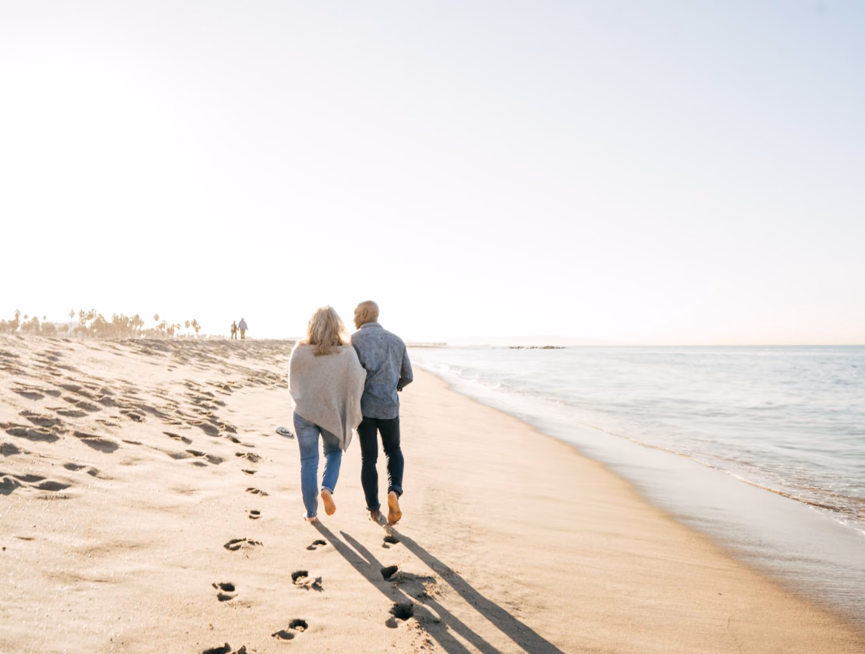 Loving couple walking barefoot on the beach.