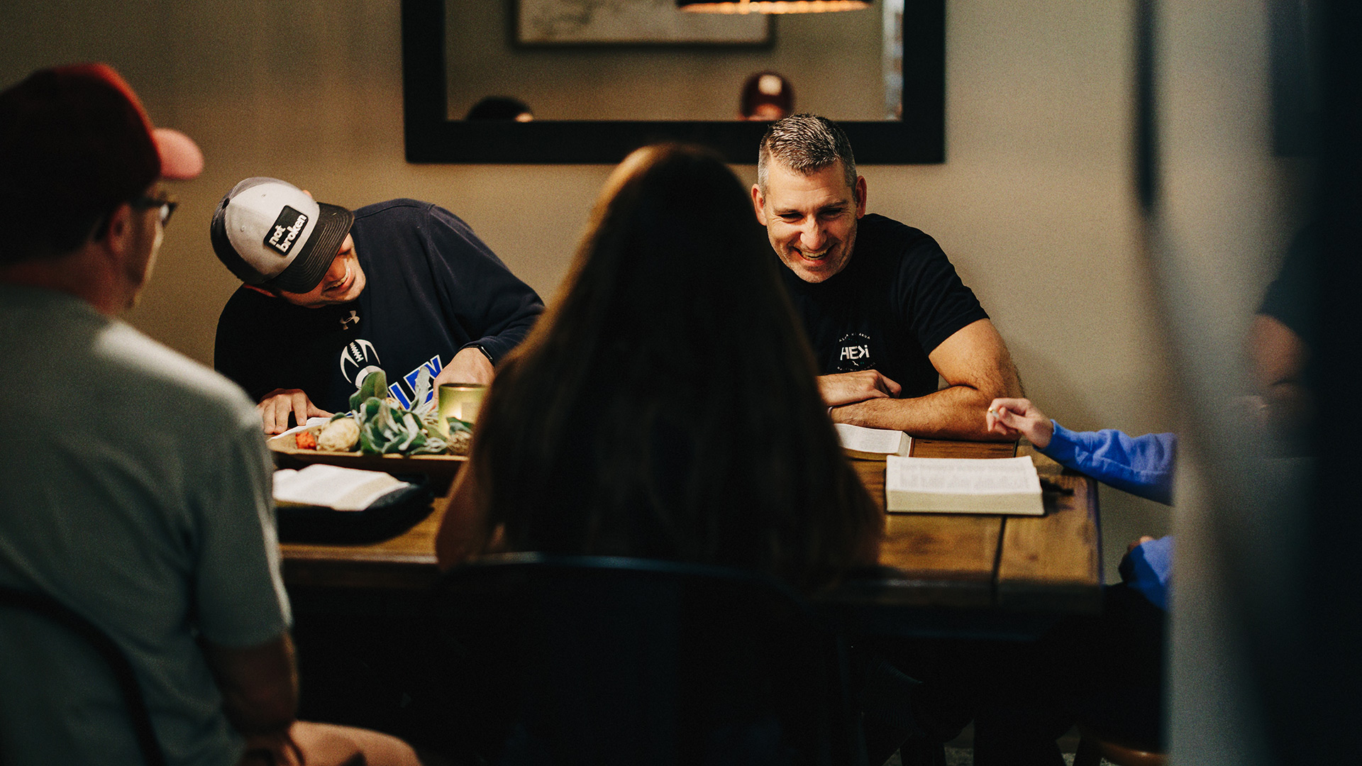 Small group from Northwest Bible Church laughing and chatting together around a dining room table during Bible study