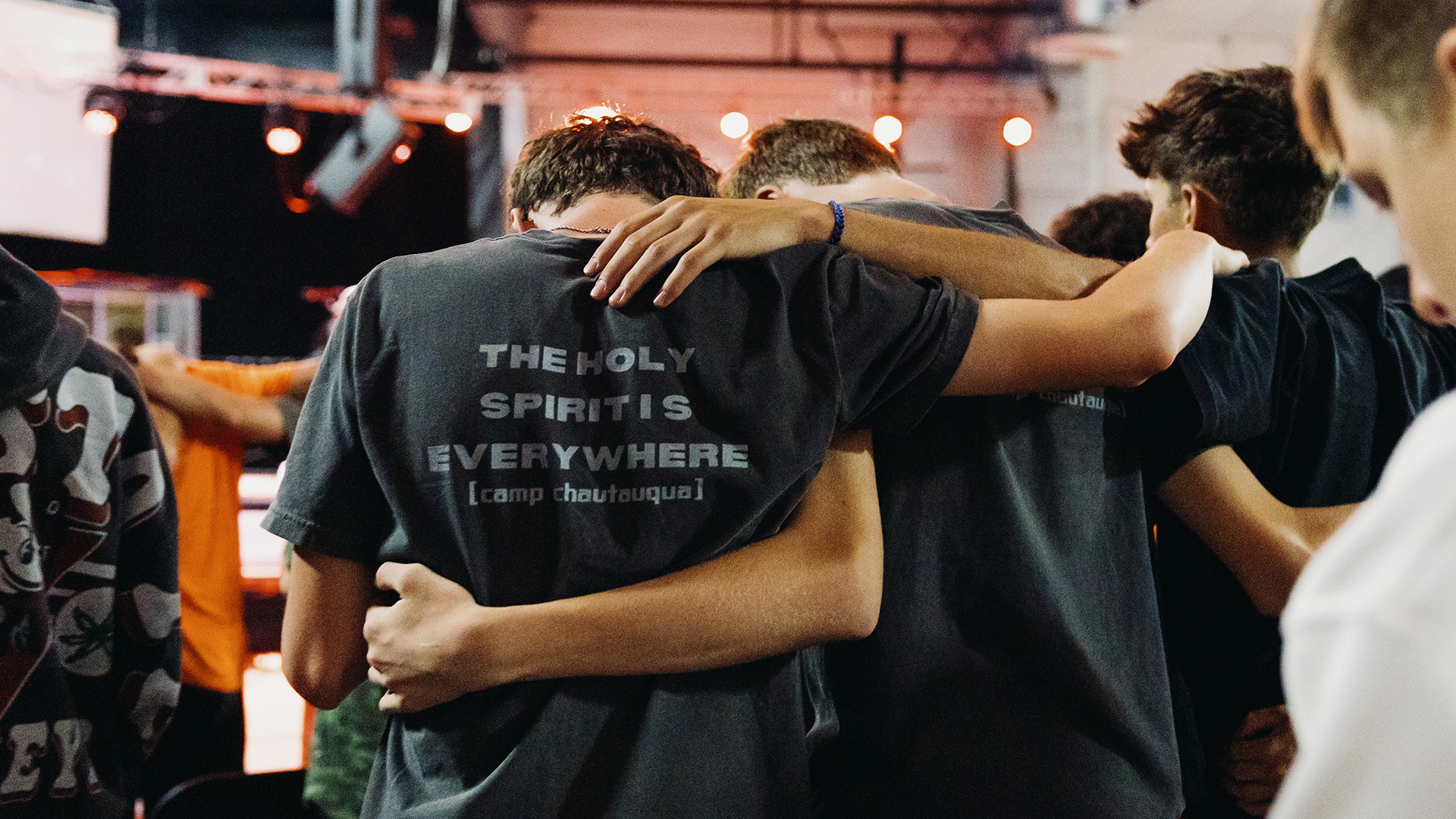 students with their arms around eachother during worship