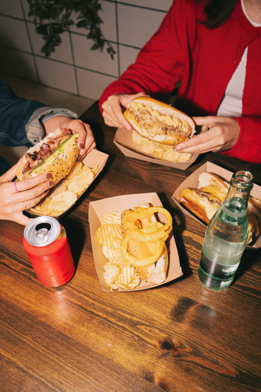 A woman is holding a sandwich and a drink.