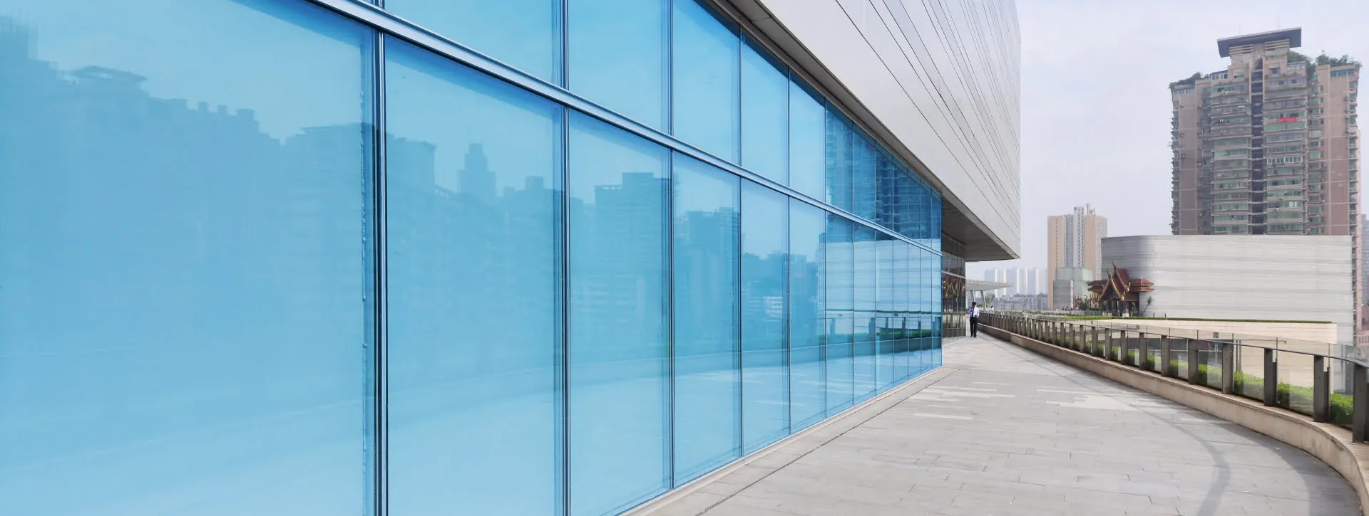 Large blue glass windows on modern curved building with urban backdrop