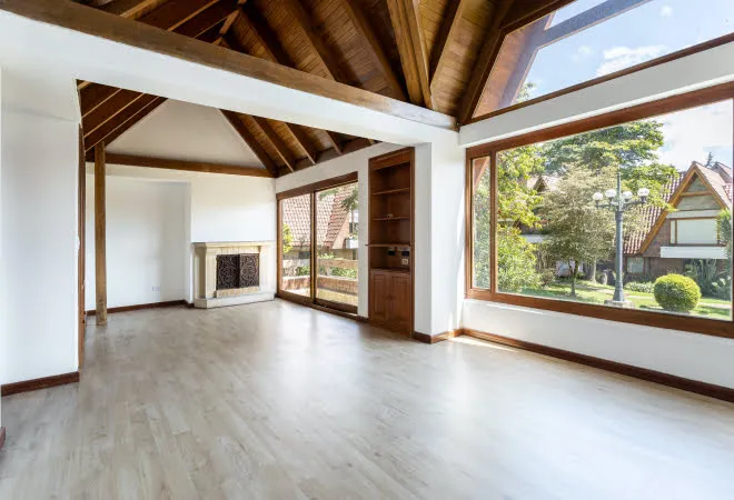 Empty room with large wooden windows overlooking lush green garden landscape
