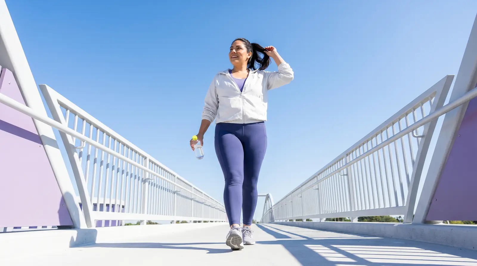 Woman striding across a bridge under an open sky, energized — NAD+ injection therapy from GobyMeds