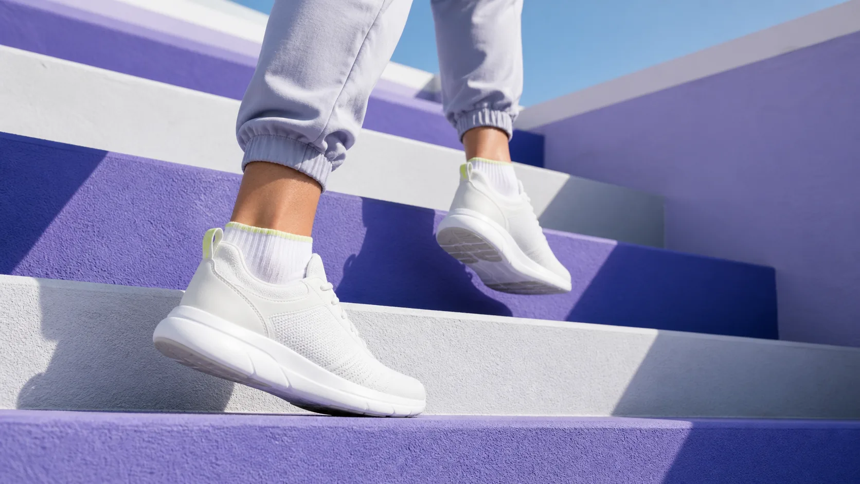 Close-up of white sneakers climbing violet-painted outdoor stairs