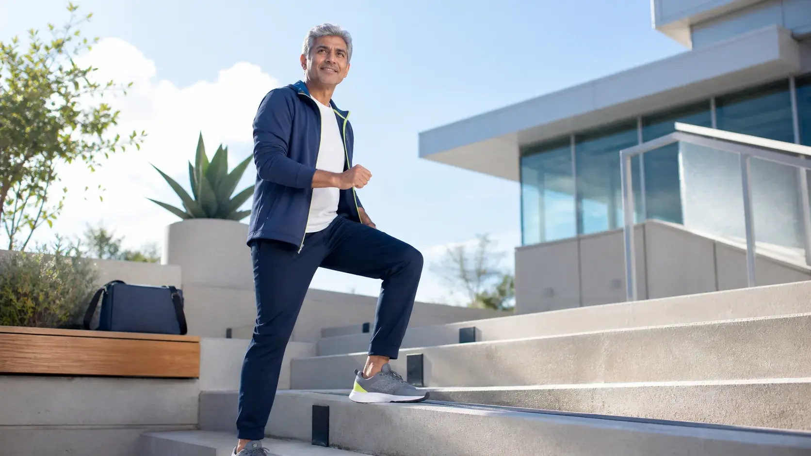 Silver-haired man climbing outdoor steps in the sun — GobyMeds longevity treatments for men