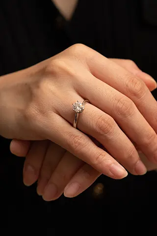 Crossed hands with a solitaire diamond ring.