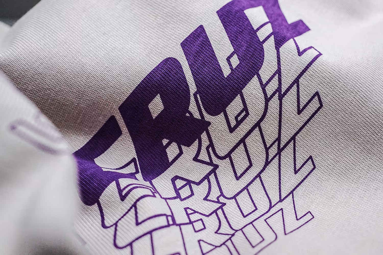 A close-up picture of a water base screen print featuring the  word cruz in purple ink.