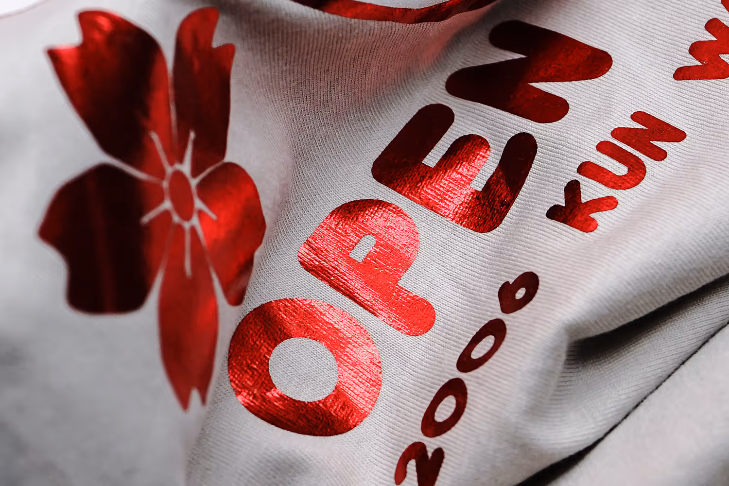 A cose up image of a red foil print featuring the word open in bright red foil.