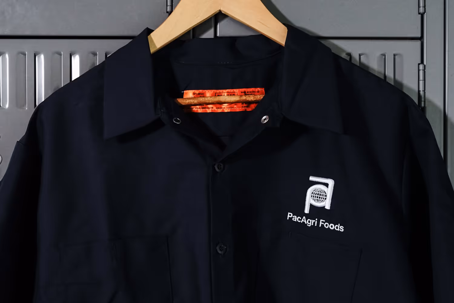 An image of an embroidered work shirt hanging on a locker door.