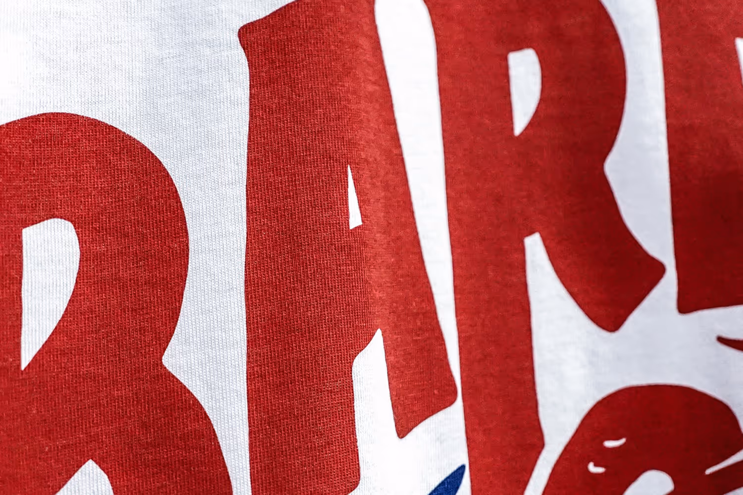 A close-up image of bright red letters printed on a white shirt using water base ink.