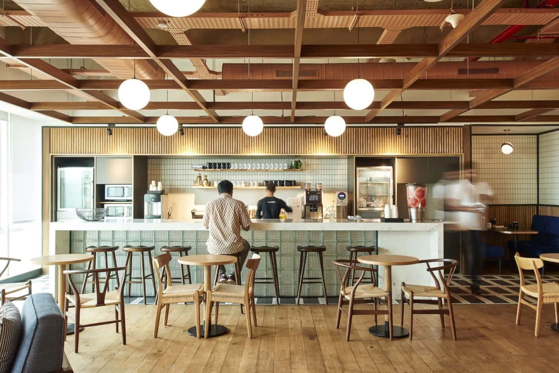 “Contemporary coworking kitchen café blending bar seating, wooden furniture, and soft warm lighting.