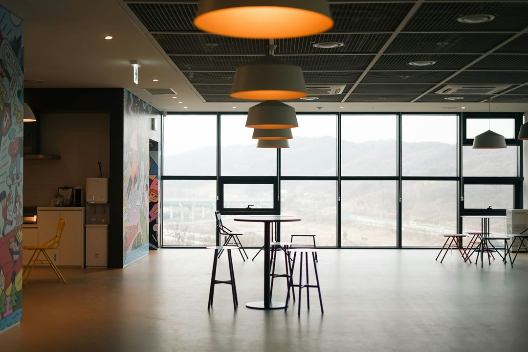 Contemporary office breakout area with pendant lighting, high seating, and panoramic window views.