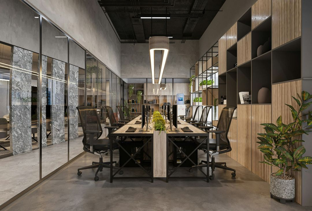 Modern open-plan office with long shared desks, ergonomic chairs, glass meeting rooms, and wood-accented shelving with greenery.
