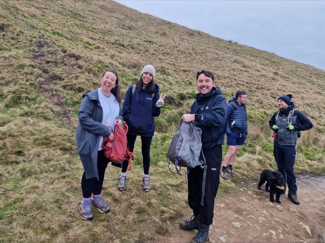 Team enjoying an outdoor group hike on a grassy hillside during a company wellbeing activity.