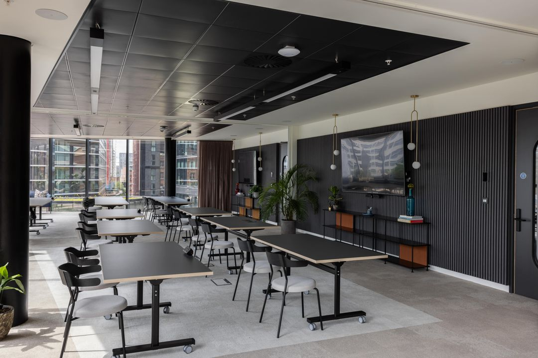 Premium serviced office event and coworking space with modular desks, large windows, and stylish black-and-wood interiors.