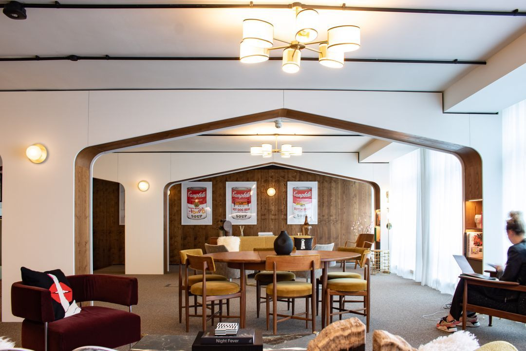 Stylish modern office lounge with mid-century furniture, warm wood accents, decorative archway frames, and comfortable seating for informal meetings or coworking.