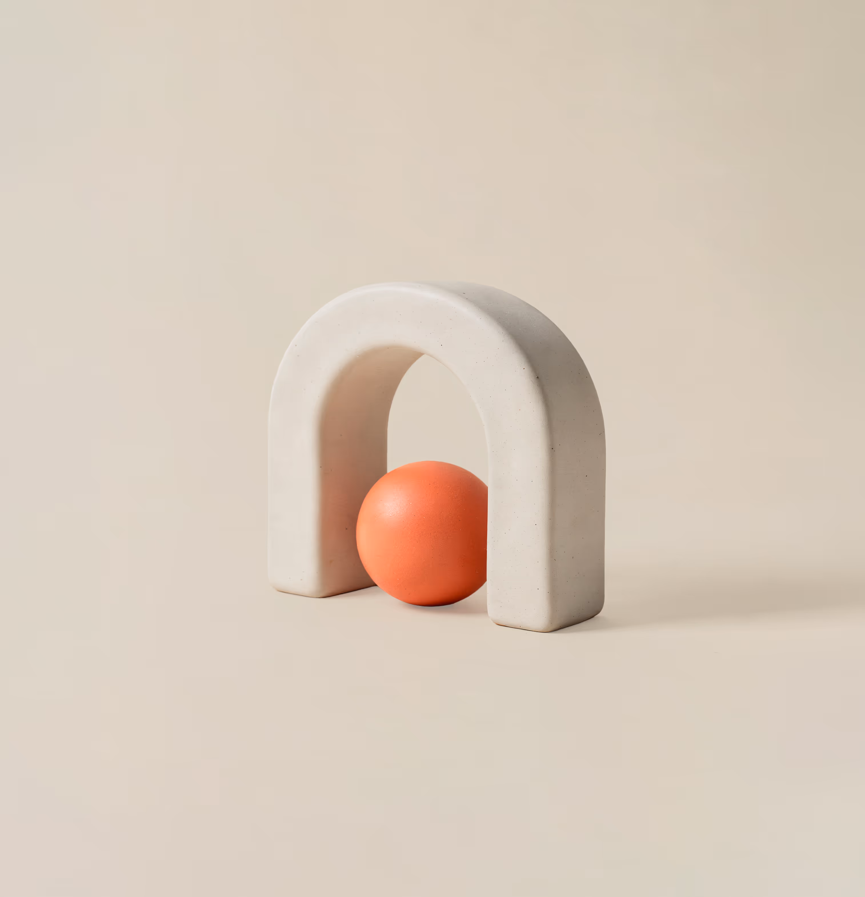 Petite arche en pierre blanche avec une sphère orange placée dessous sur fond beige.