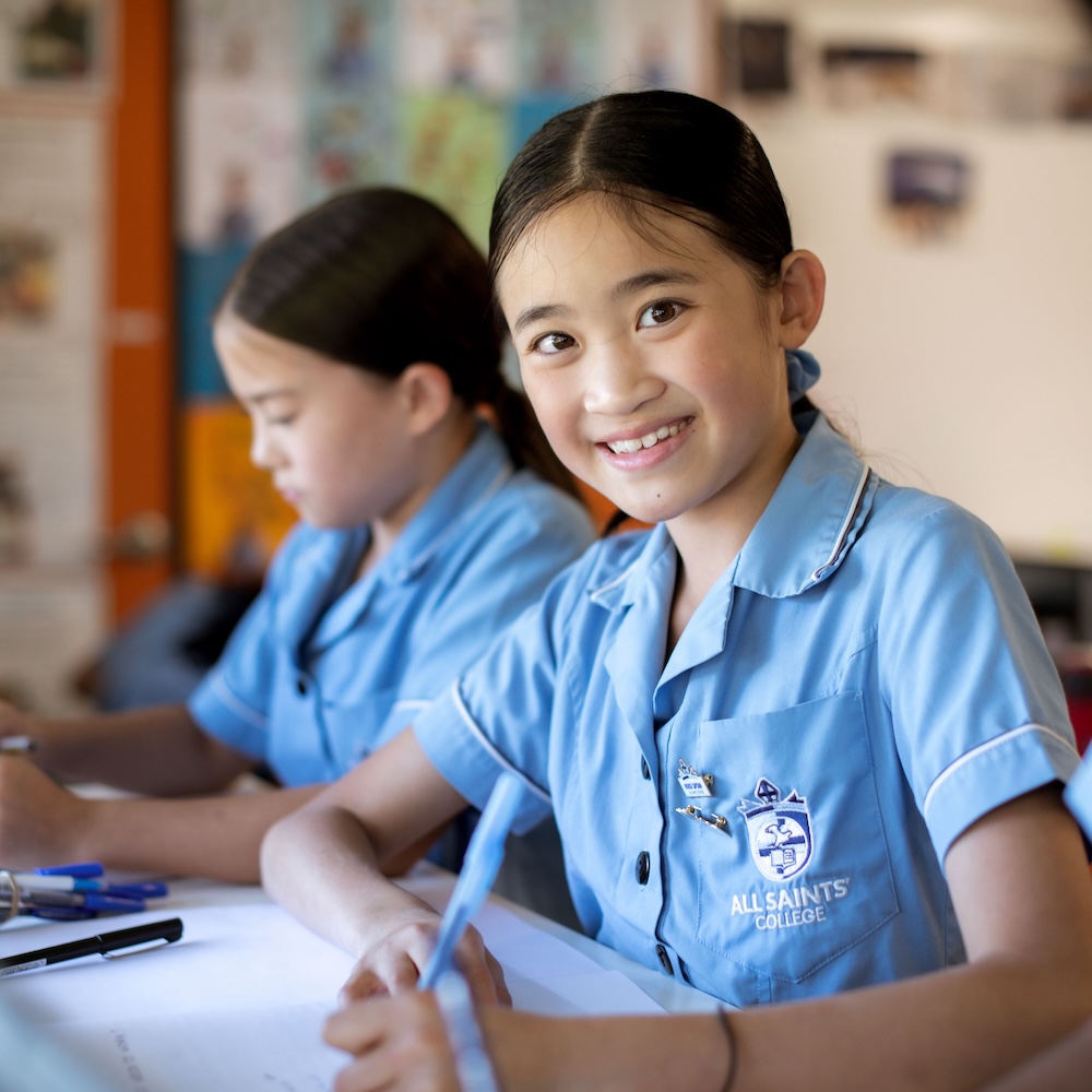A student in a blue school uniform smiling at the camera.