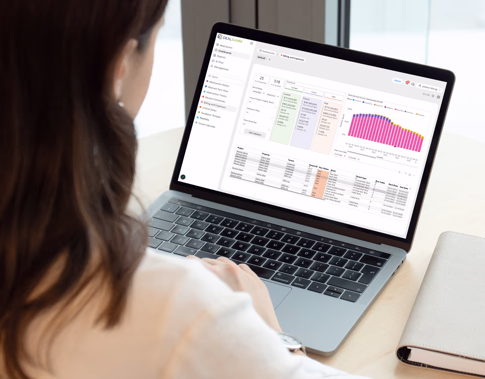 Person viewing a laptop screen displaying a DealSumm financial dashboard with charts, tables, and menu options.