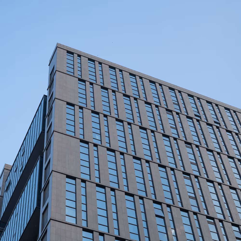 Modern high-rise office building with reflective glass windows against a clear blue sky.