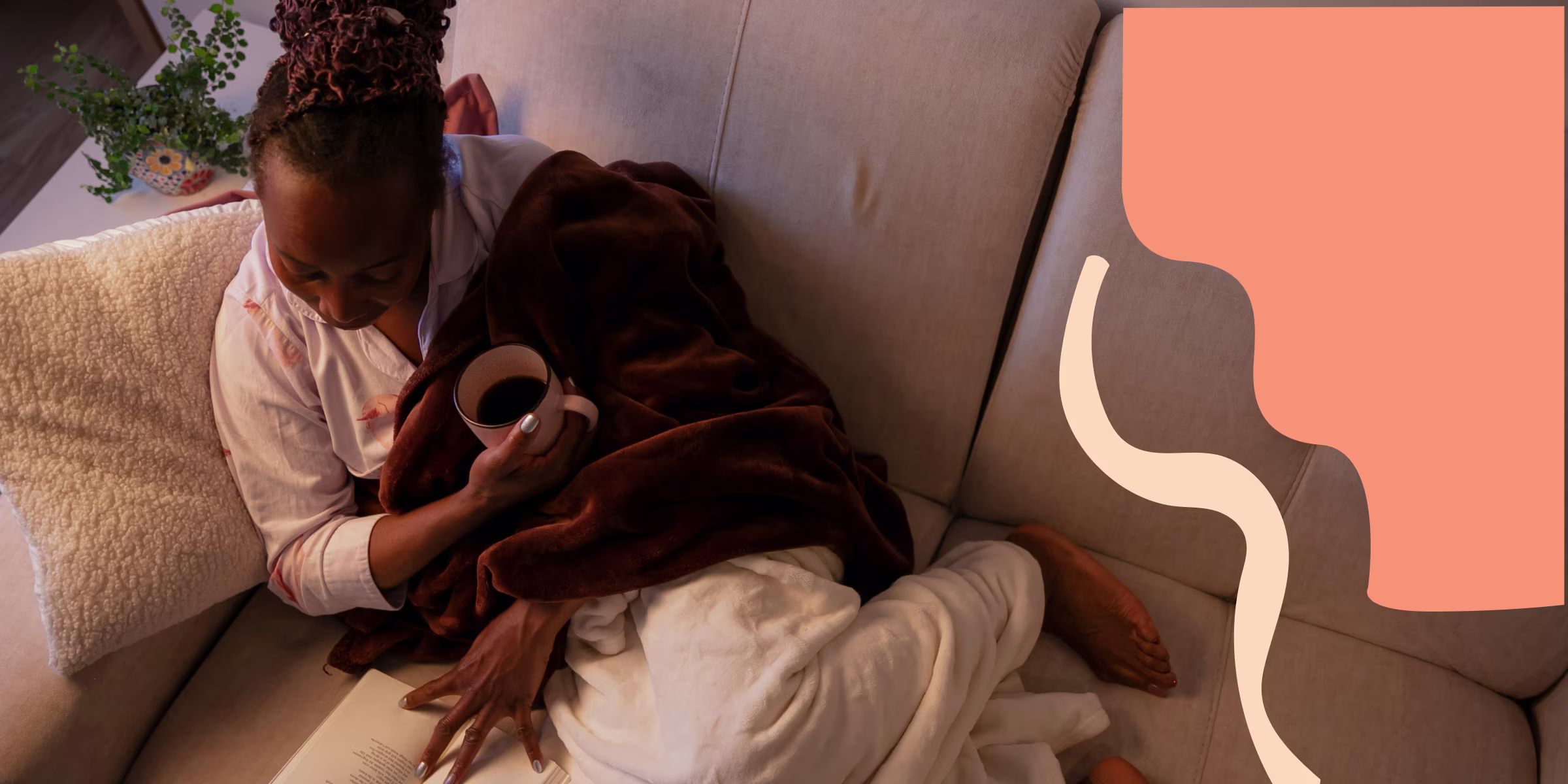 Woman relaxing on her couch with a mug of tea and a book, recovering from an abortion.