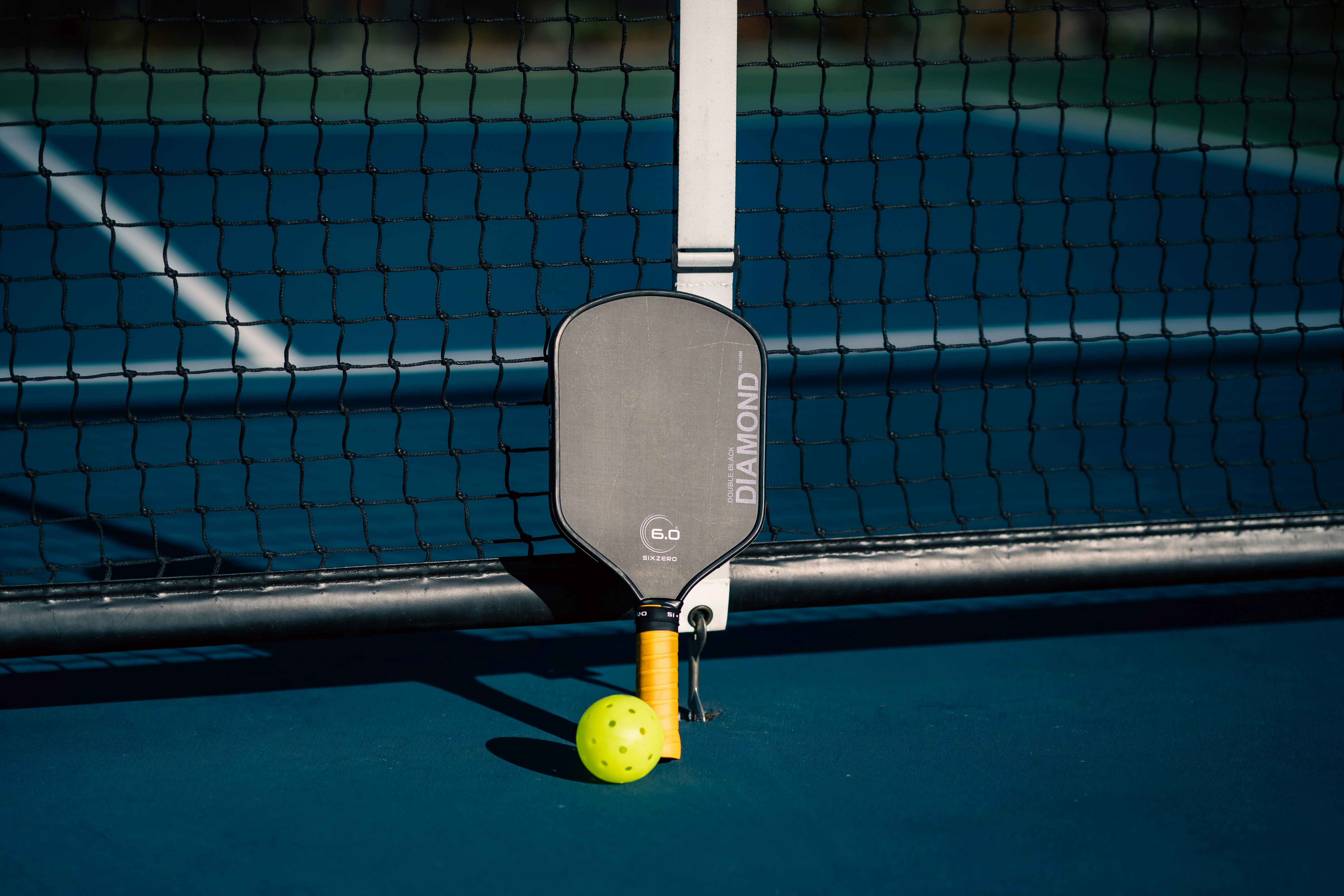 Pickleball paddle and ball on a pickleball court