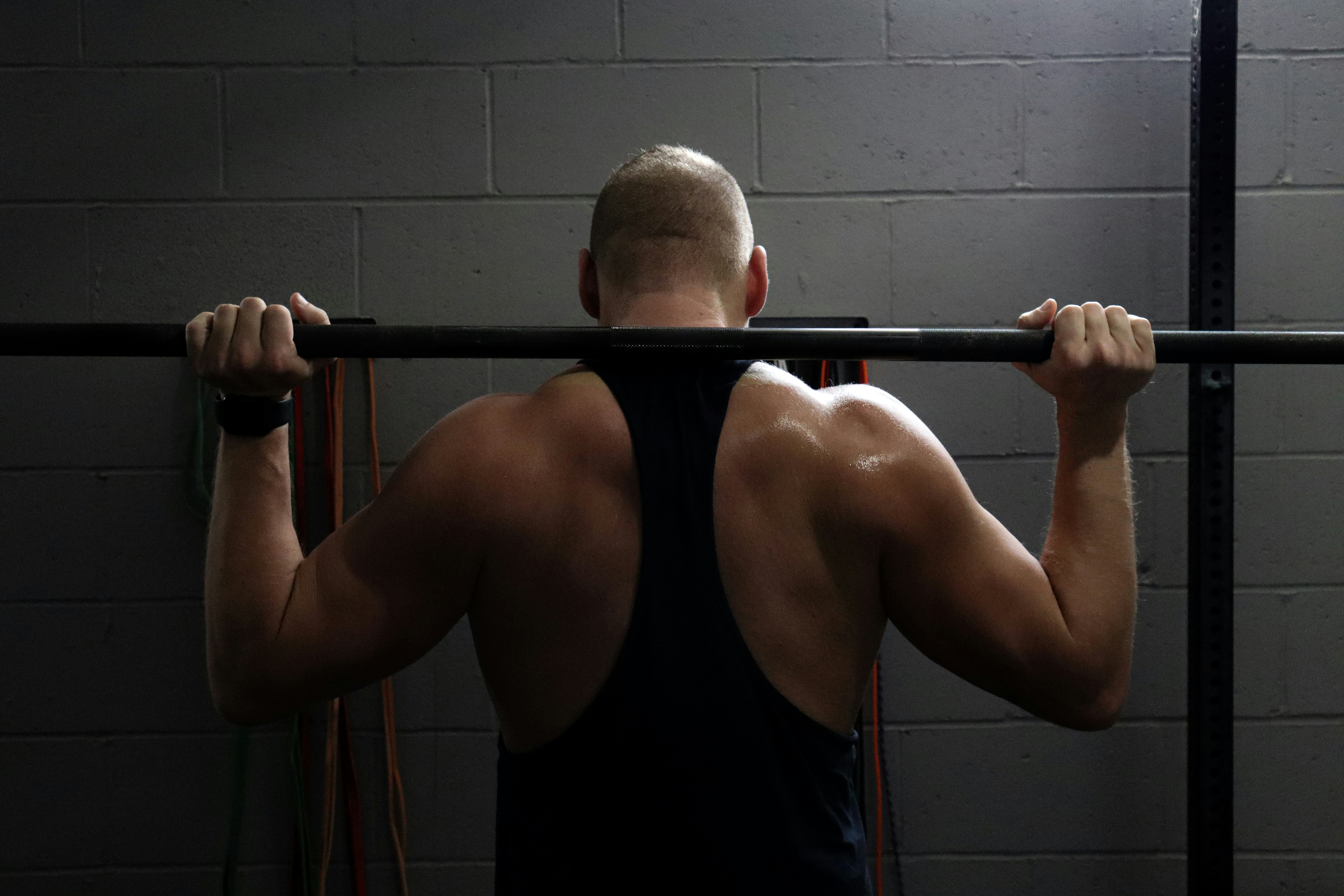 Man performing a barbell shoulder exercise in a gym