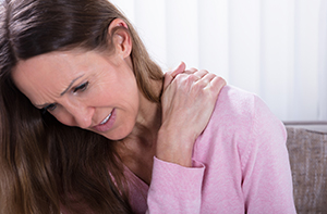 Woman holding her sore shoulder while considering a cortisone injection