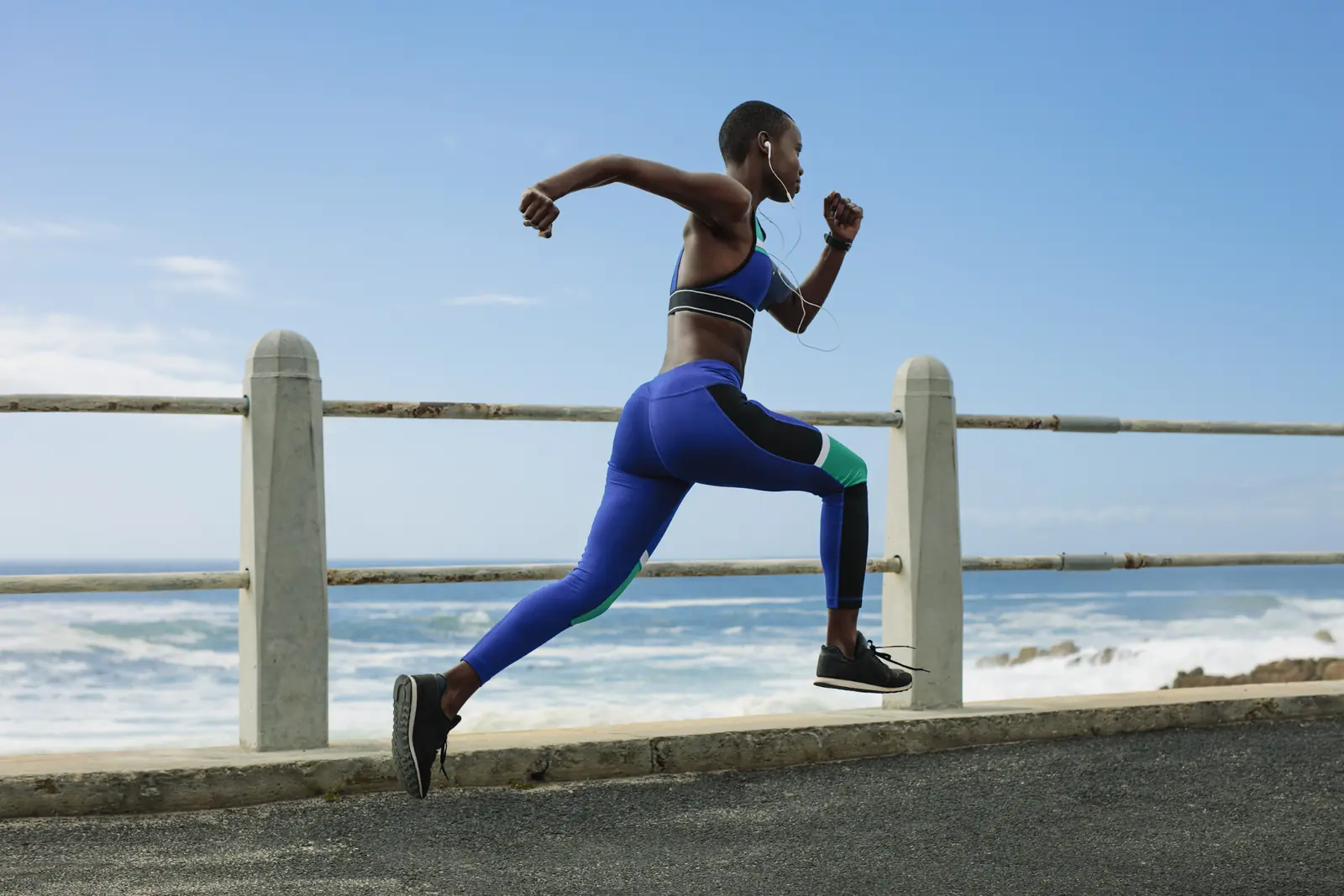 Athlete running along a seaside path during an outdoor workout.