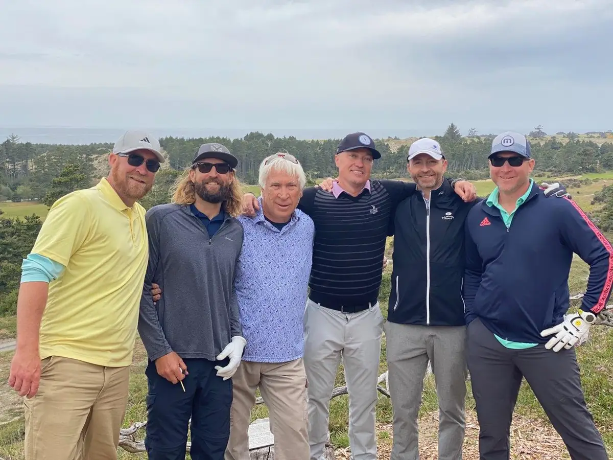Group of golfers posing together on a coastal golf course.